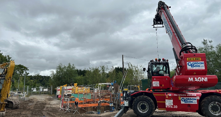 View of construction site with a portable crane on the right. A cloudy sky is overhead.