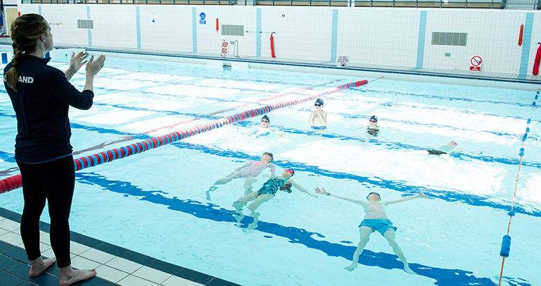 Drowning Prevention Week female instructor giving a swimming lesson with children in a swimming pool
