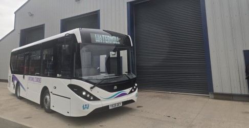 A bus with "Watermill" as its destination, parked outside a modern industrial building.