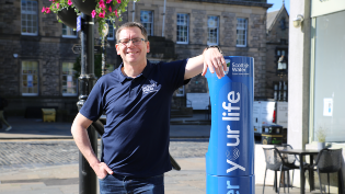 Alex Plant smiling, at a Top up Tap 