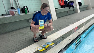 Learn to Swim teacher Caitlin Ebbage holds up new teaching cards tool at poolside